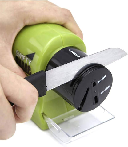 Hand holding green electric knife grinder sharpening a kitchen knife in Pakistan